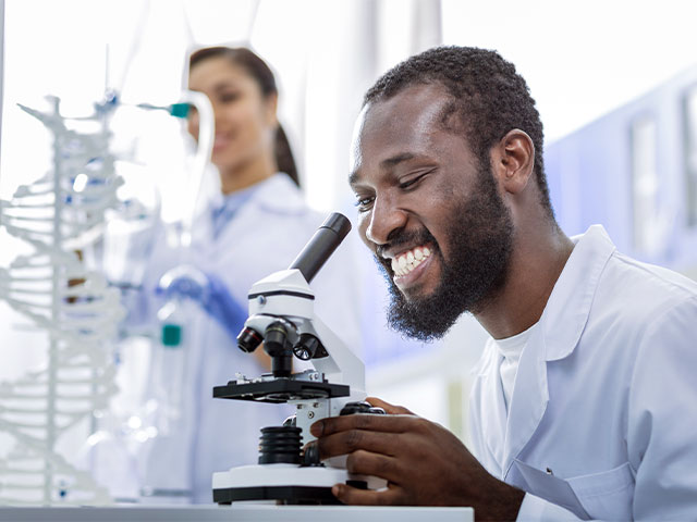 Scientist observing sample under microscope